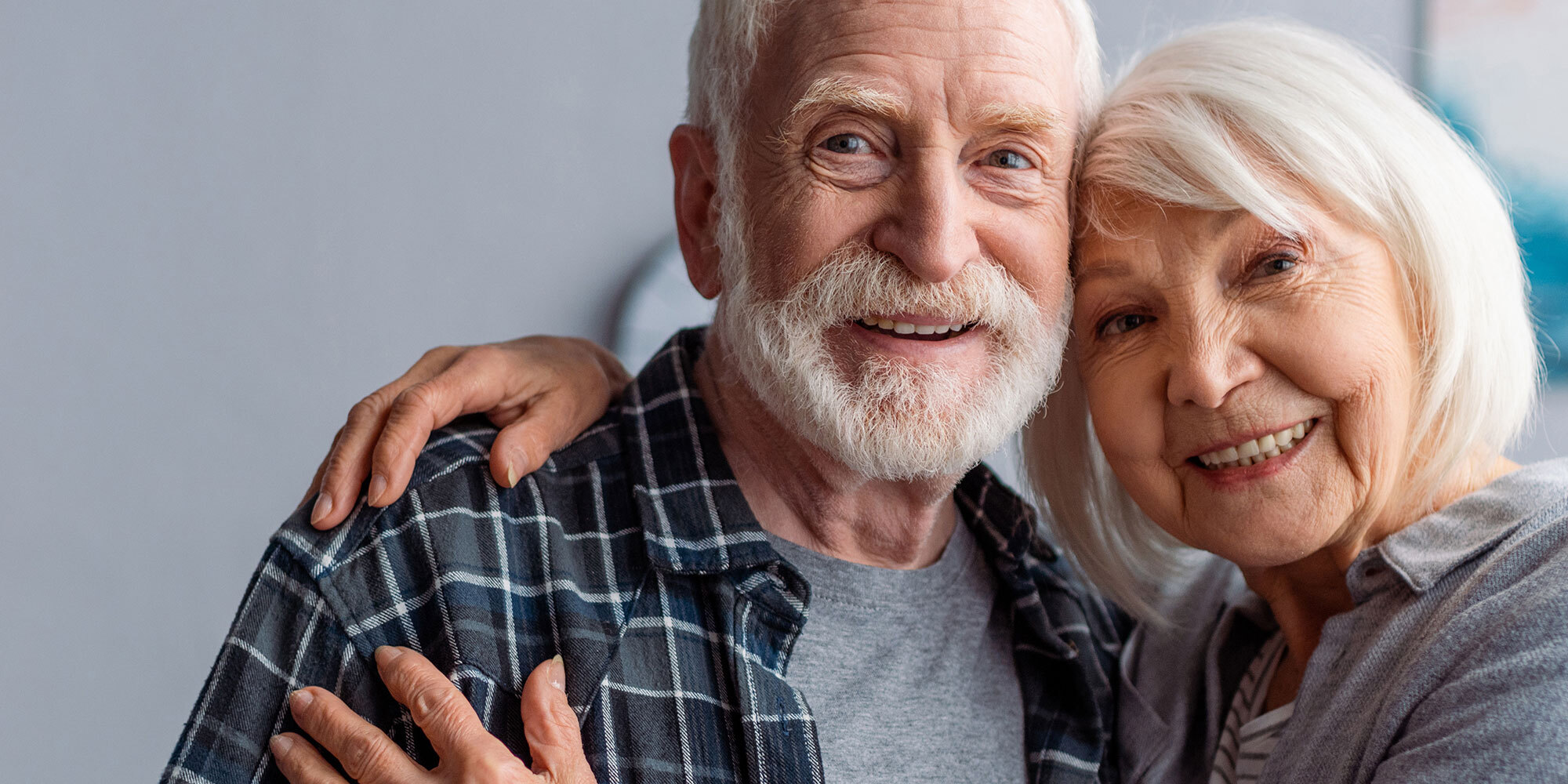 A senior couple smiling together while discussing the signs of dementia.